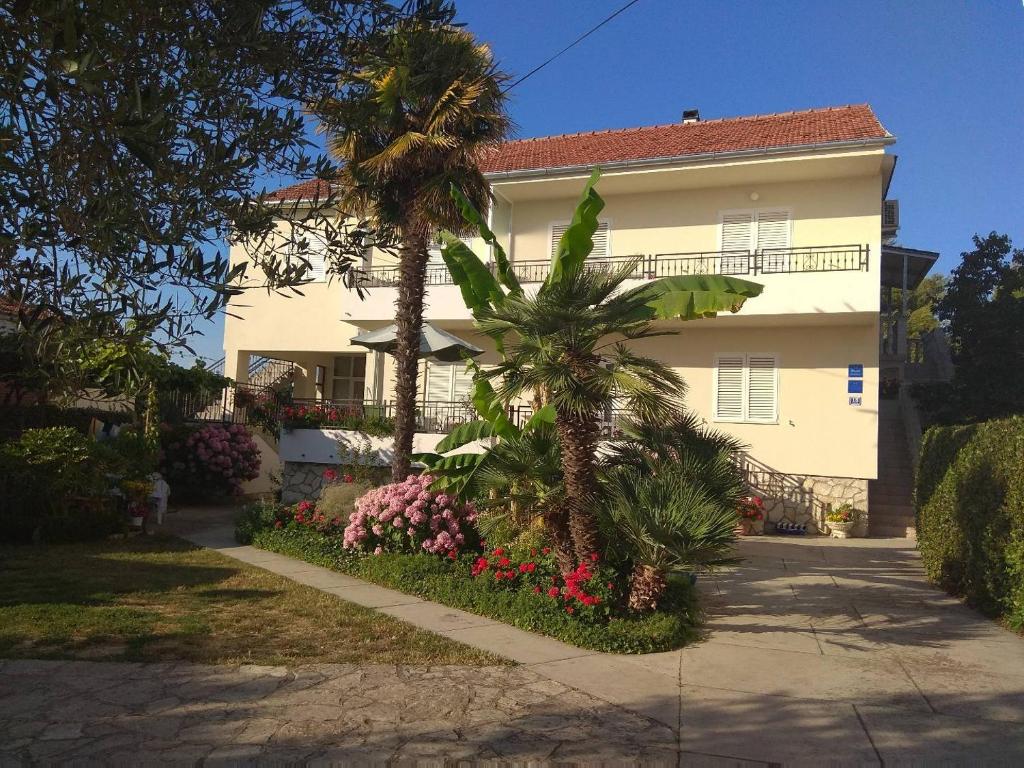 una casa con palme e fiori di fronte ad essa di Studio Apartmani Krstina a Sukošan (San Cassiano)