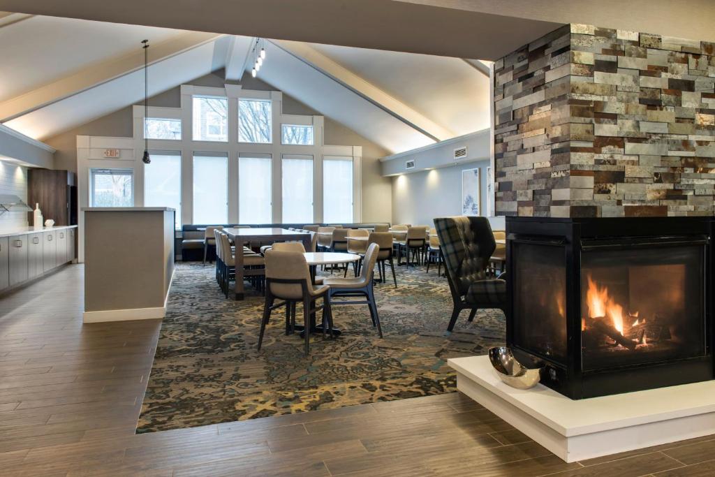 a living room with a fireplace and a dining room at Residence Inn Fairfax Merrifield in Merrifield