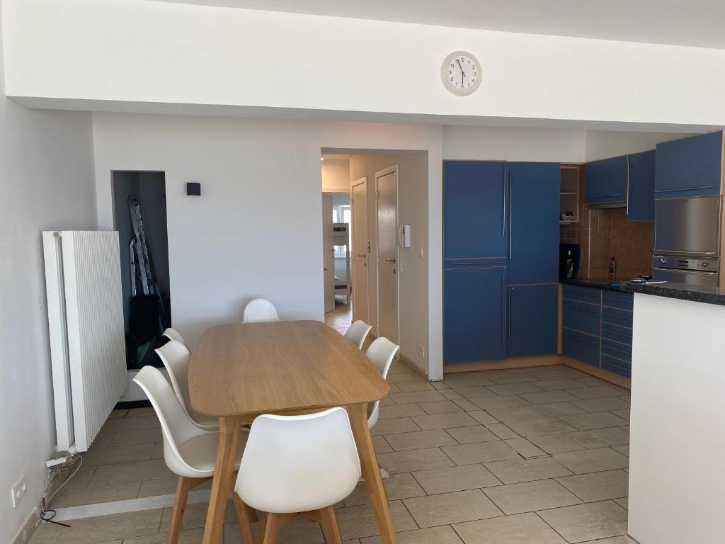 a kitchen with blue cabinets and a wooden table and chairs at Appartement vue sur mer - Splendide localisation! in Sint-Idesbald