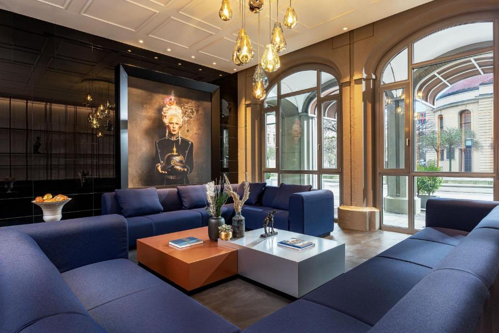 ein Wohnzimmer mit blauen Sofas und einem Tisch in der Unterkunft Hotel Luc, Autograph Collection in Berlin