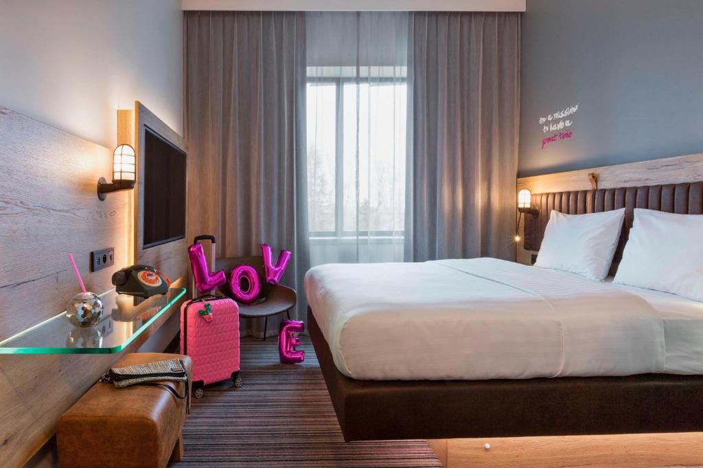 a hotel room with a large bed and a desk with at Moxy Katowice Airport in Pyrzowice