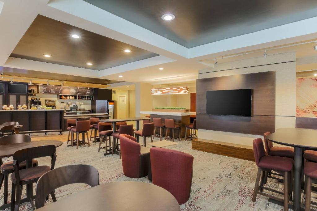 a restaurant with tables and chairs and a flat screen tv at Courtyard by Marriott Monroe Airport in Monroe