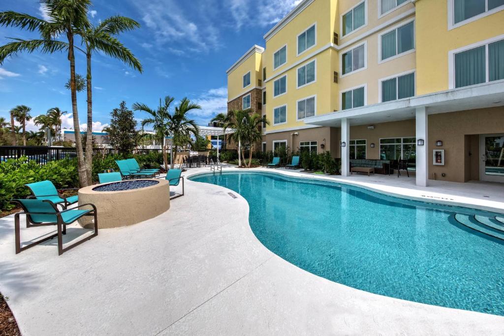 Residence Inn Fort Lauderdale Pompano Beach Central في بومبانو بيتش: مسبح وكراسي ومبنى