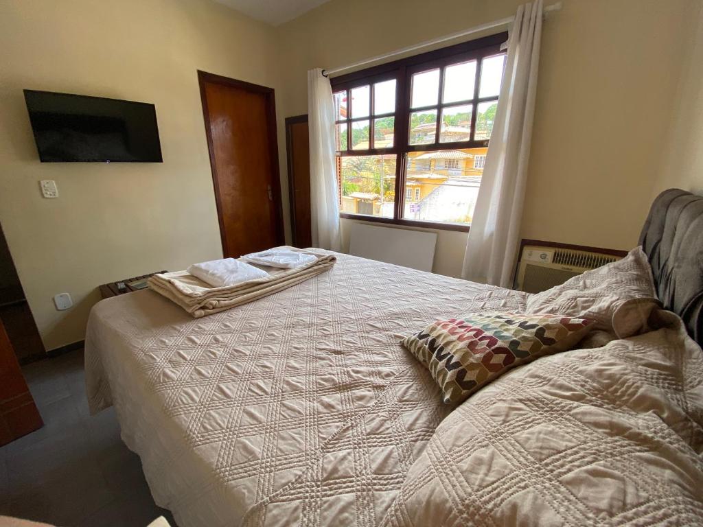 um quarto com uma cama e uma janela em Pousada Maricá em Maricá