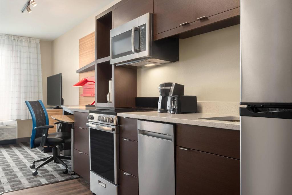 cocina con electrodomésticos de acero inoxidable y mesa en TownePlace Suites by Marriott Janesville, en Janesville