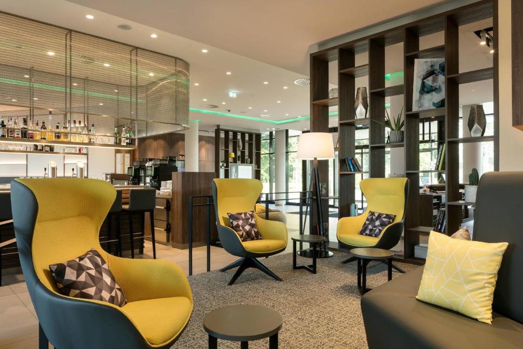 a lobby with yellow chairs and a bar at Courtyard by Marriott Wolfsburg in Wolfsburg