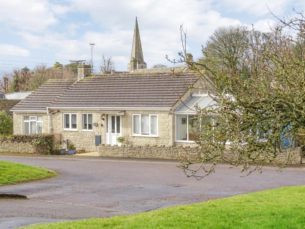 a house with a church steeple in the background at The Churn in Bisley