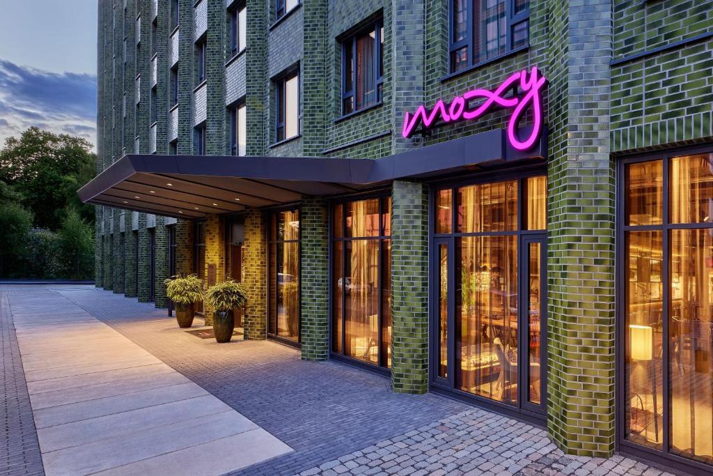 un grand bâtiment en briques avec un panneau de néon sur lui dans l'établissement Moxy Cologne Muelheim, à Cologne