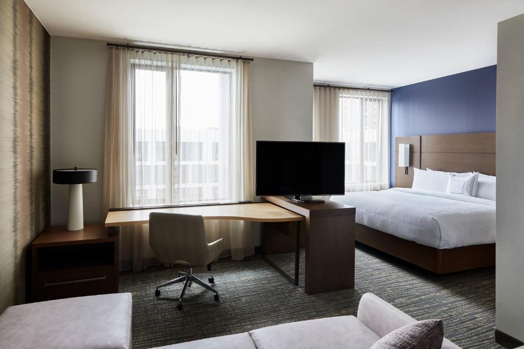 a hotel room with a bed and a desk with a television at Residence Inn By Marriott Dallas By The Galleria in Dallas