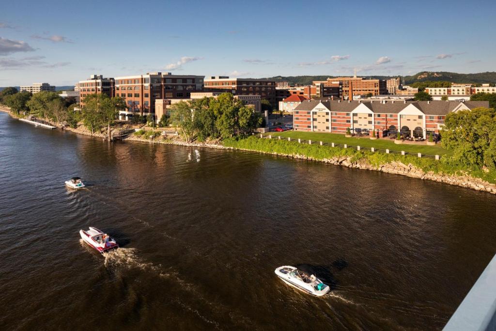 deux bateaux dans une rivière avec des bâtiments en arrière-plan dans l'établissement Courtyard La Crosse Downtown/Mississippi Riverfront, à La Crosse