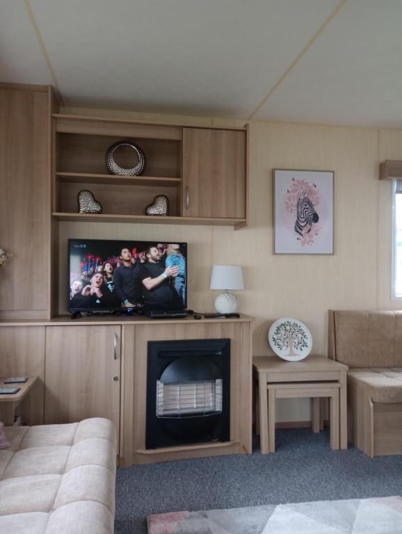 ein Wohnzimmer mit einem TV und einem Kamin in der Unterkunft A22 is a 3 bedroom caravan on Whitehouse Leisure Park in Towyn near Abergele with decking and close to sandy beach in Conwy