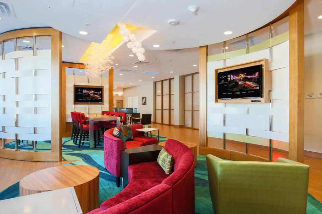 a lobby with red chairs and a dining room at SpringHill Suites by Marriott San Jose Airport in San Jose