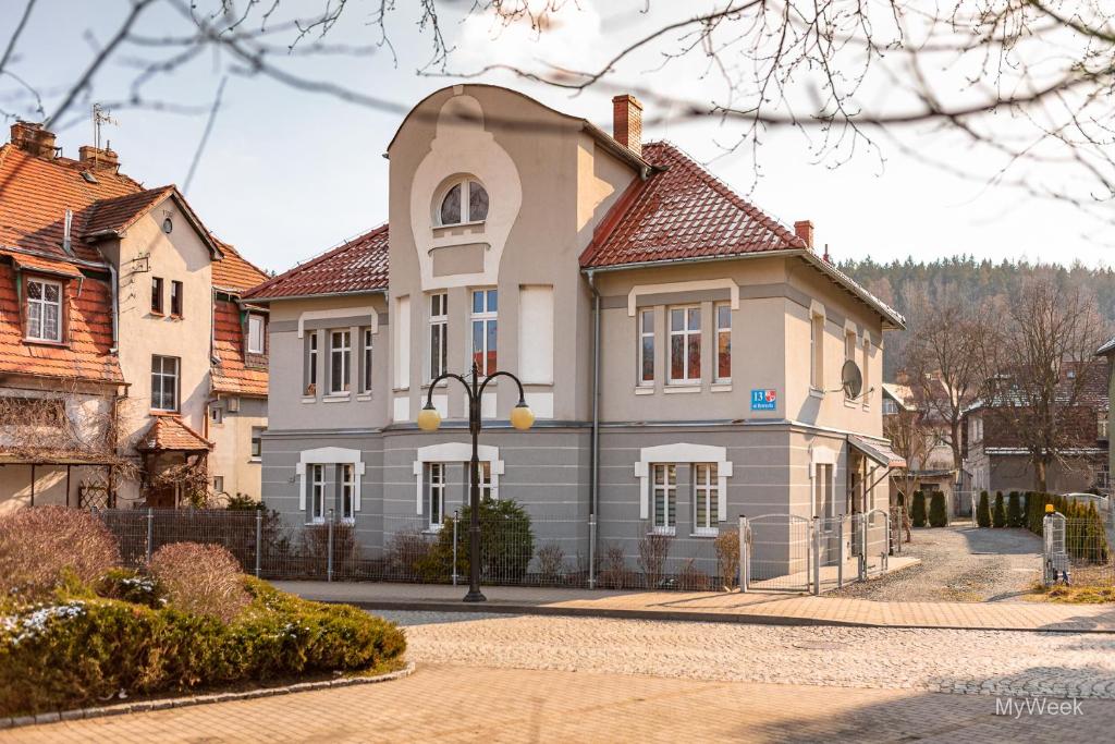 uma grande casa branca com uma torre numa rua em Apartament na deptaku, MyWeek em Polanica-Zdrój