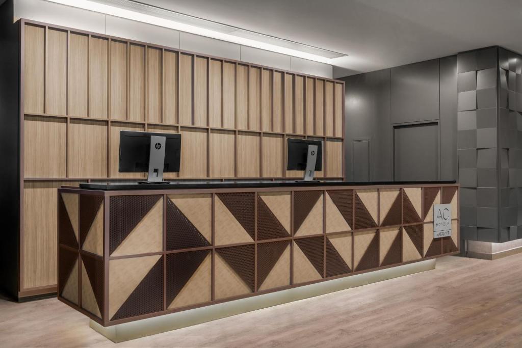 a lobby with a reception desk with two monitors at AC Hotel Coslada Aeropuerto by Marriott in Coslada