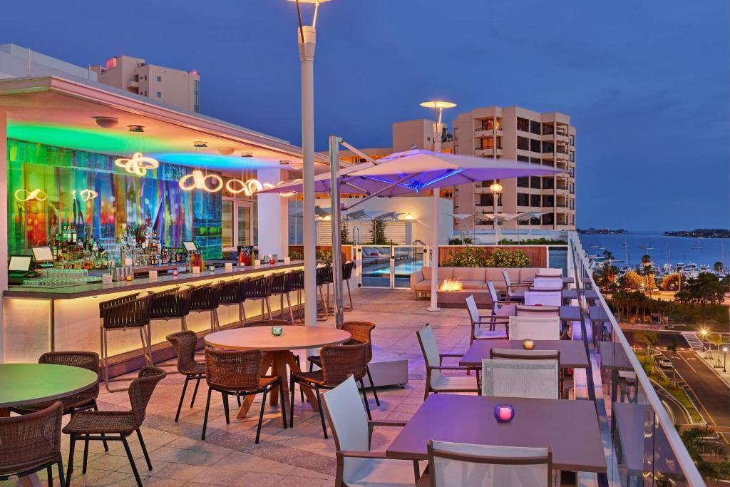 a rooftop patio with tables and chairs and a bar at Art Ovation Hotel, Autograph Collection in Sarasota