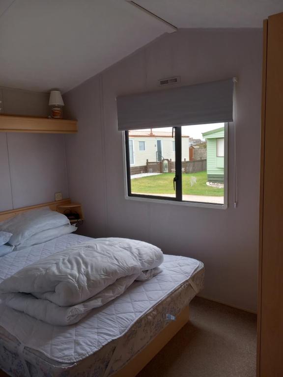 a bedroom with a bed and a window at Melody Brooks Caravan Park in Portknockie