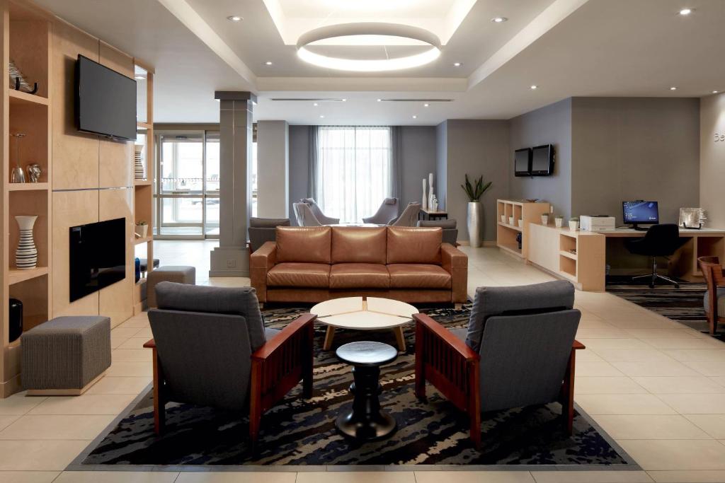 ein Wohnzimmer mit einem Sofa, einem Tisch und Stühlen in der Unterkunft Fairfield Inn & Suites by Marriott Montreal Airport in Dorval