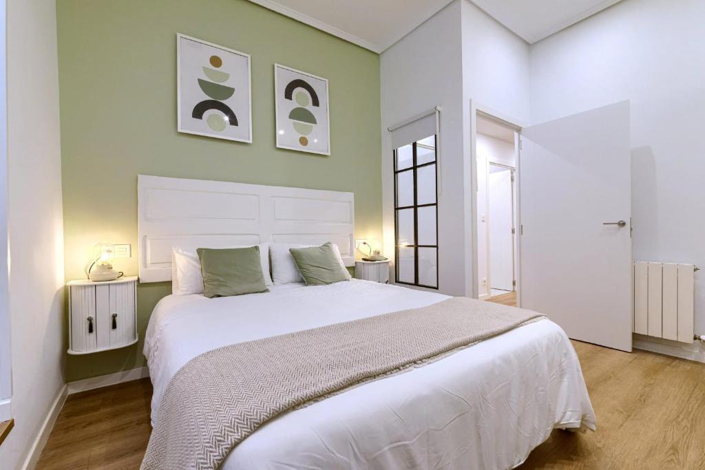 Un dormitorio con una gran cama blanca con paredes verdes. en Roomscapital, en Bilbao
