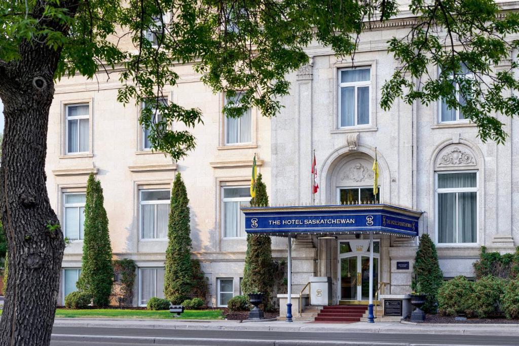 ein weißes Gebäude mit einem blauen Schild davor in der Unterkunft The Hotel Saskatchewan, Autograph Collection in Regina