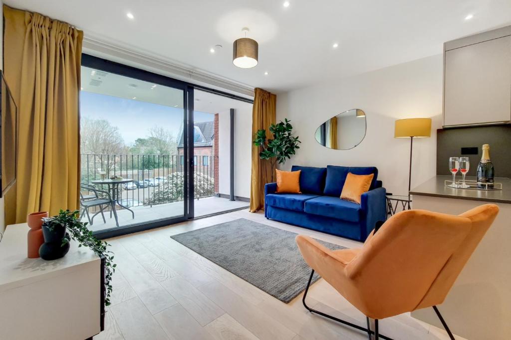 a living room with a blue couch and a balcony at Luxury Harrow Wembley Apartment in Harrow