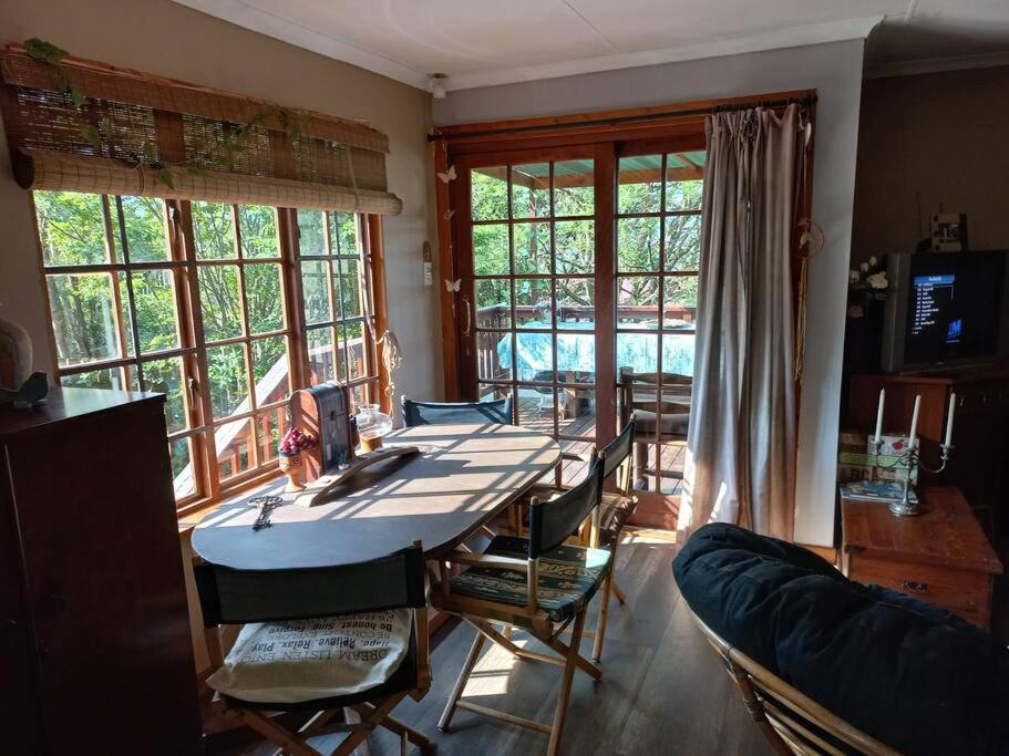 a living room with a table and chairs and windows at The Big tree @ Sabie in Sabie