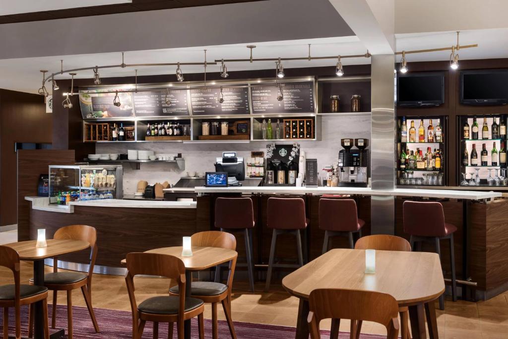 a bar in a restaurant with tables and chairs at Courtyard Syracuse Carrier Circle in East Syracuse