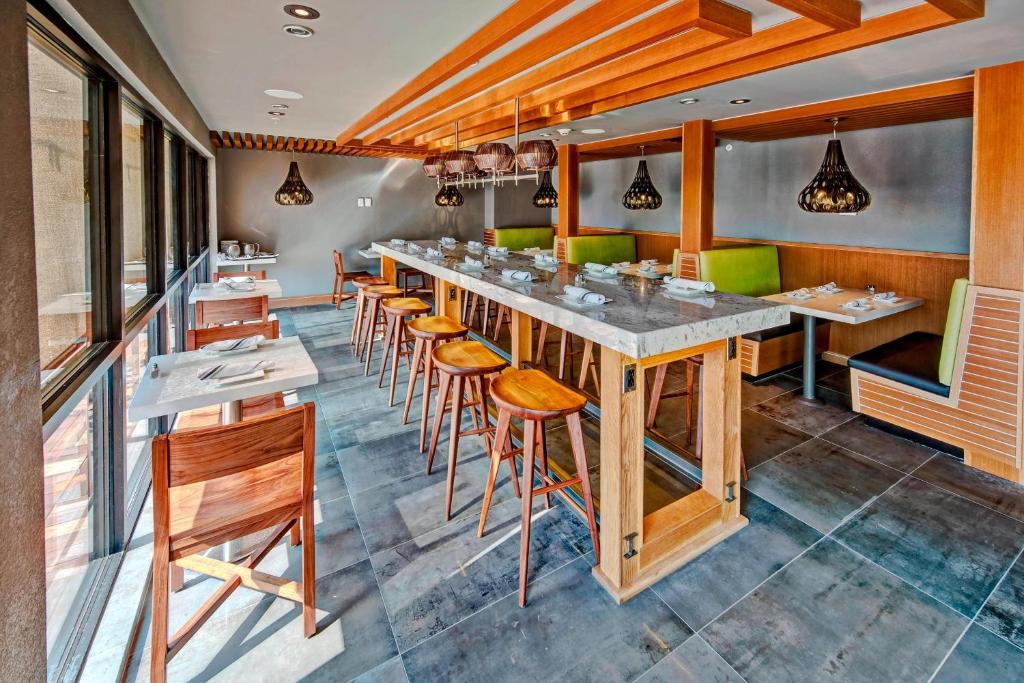 un restaurante con un bar largo con taburetes de madera en Courtyard by Marriott Oxford en Oxford