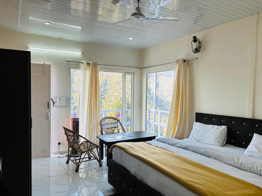 a bedroom with a bed and a table and a window at IN APPLE ESTATE KANATAL - Himalayan View Resort with Courteous Staff in Kanatal