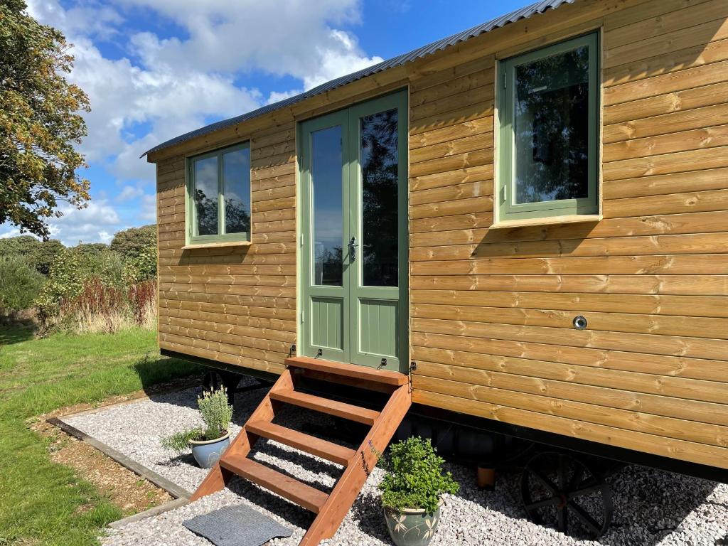 a tiny house with a green door and a bench at Cosy Shepherd Huts near Newborough Forest Anglesey in Gaerwen