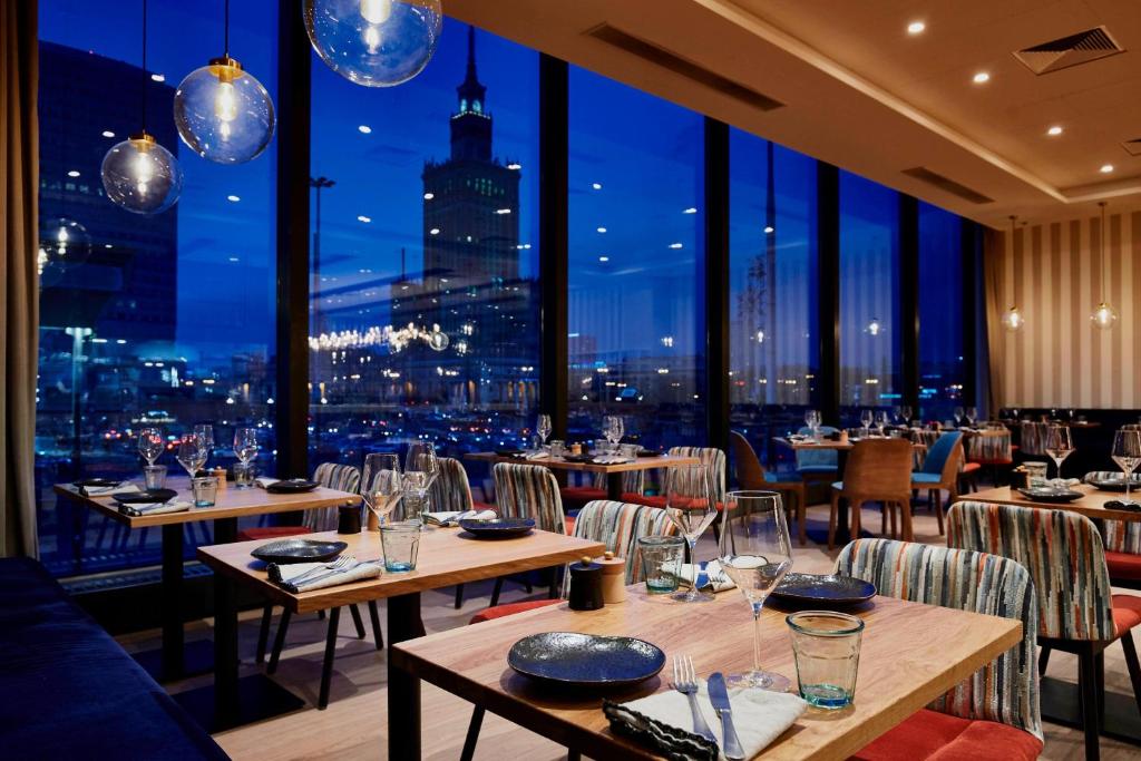 restauracja ze stołami i krzesłami oraz widokiem na miasto w obiekcie Warsaw Marriott Hotel w Warszawie