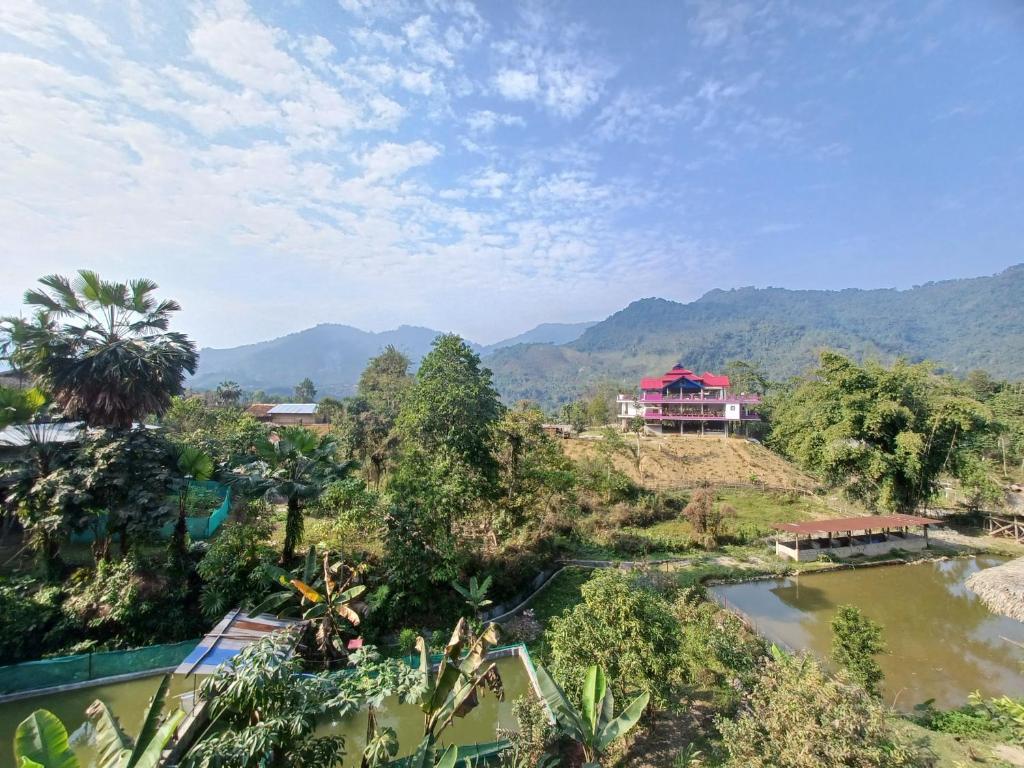 a house on a hill next to a river at Odyssey Stays Aalo in Along