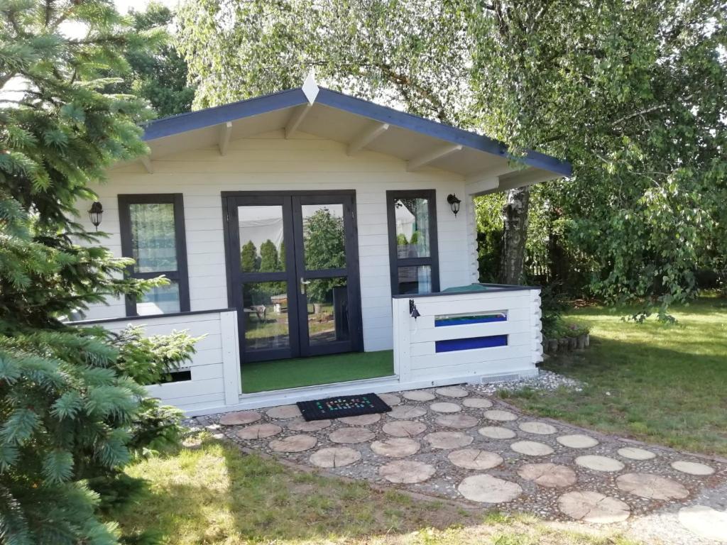 a small white shed with a blue roof at Domek letniskowy SZUWAREK in Świnoujście