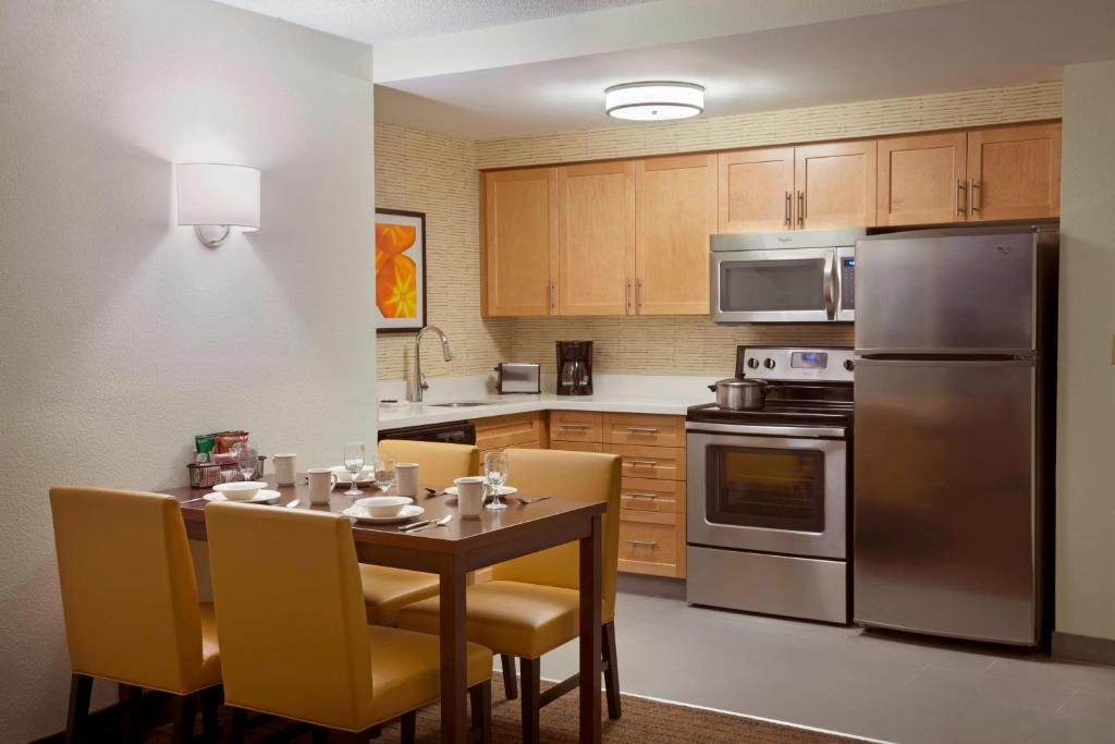 a kitchen with a table with yellow chairs and stainless steel appliances at Residence Inn by Marriott Toronto Markham in Markham