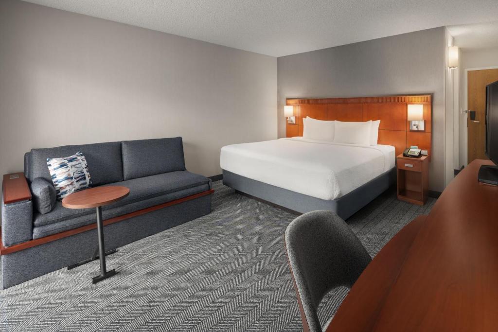 une chambre d'hôtel avec un lit et un canapé dans l'établissement Courtyard by Marriott Portland Beaverton, à Beaverton