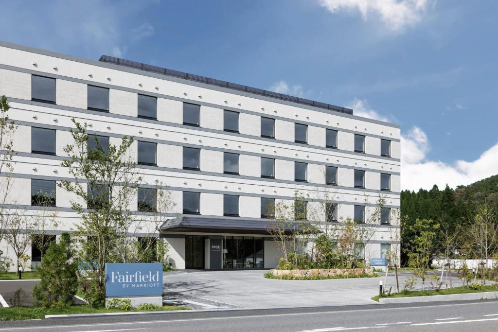 un edificio blanco con un cartel delante en Fairfield by Marriott Okayama Hiruzen Highland, en Maniwa