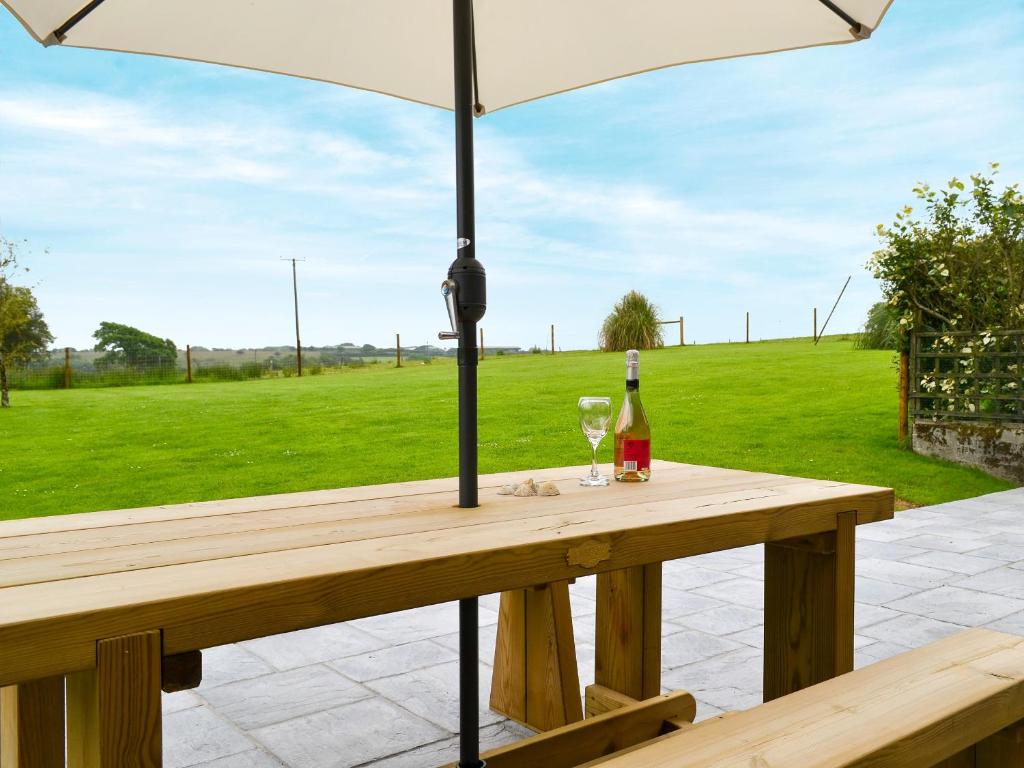 - une table en bois avec un parasol et une bouteille de vin dans l'établissement Old Mill- 23398, à Bradworthy