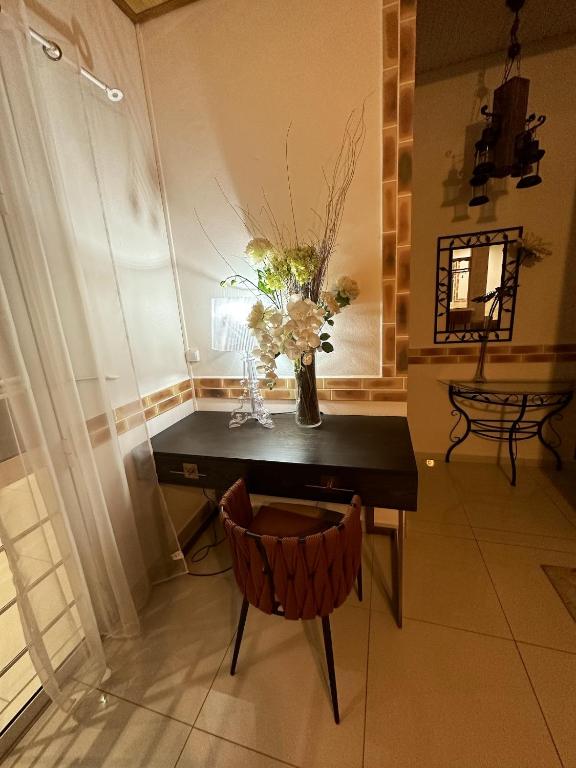 a table with a vase of flowers and a chair at Maison de 3 chambres avec piscine privee jardin clos et wifi a Sainte Rose in Sainte-Rose