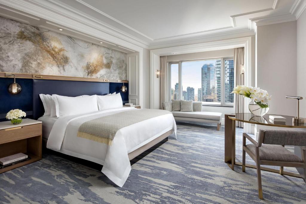 - une chambre avec un grand lit et une grande fenêtre dans l'établissement The St. Regis Toronto, à Toronto