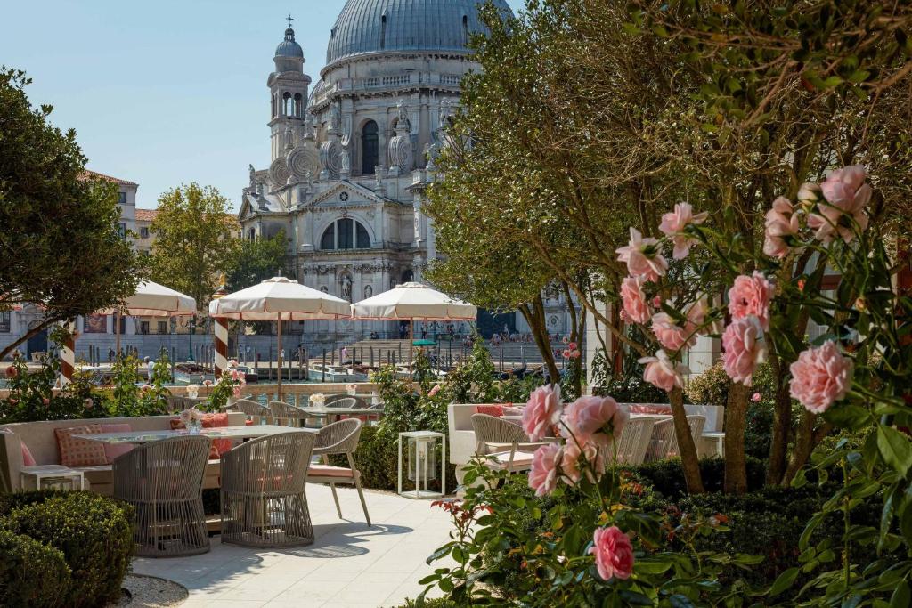 um jardim com mesas e cadeiras e um edifício em The St. Regis Venice em Veneza