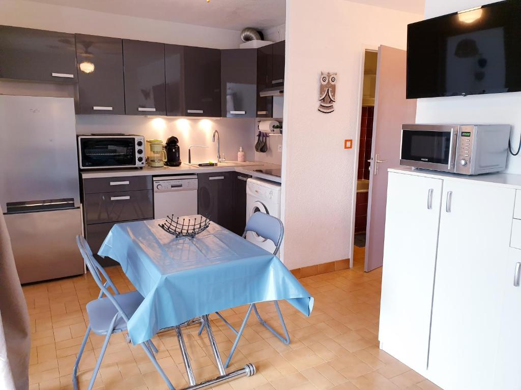 - une cuisine avec une table bleue et des chaises dans l'établissement JEAN BART I Joli T2 cabine proche plage Richelieu Cap d'Agde, au Cap d'Agde