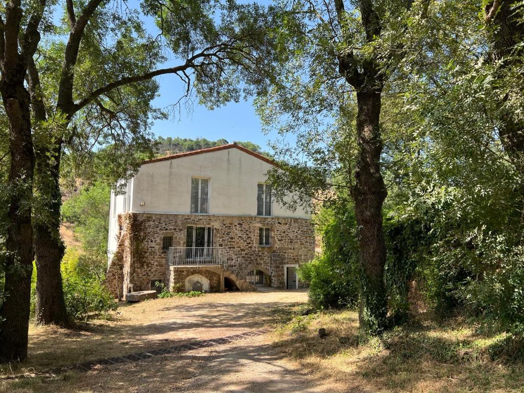 stary kamienny dom z drzewami przed nim w obiekcie Le Moulin de Prades 4 étoiles logement entier Parc Naturel Haut Languedoc - Salagou w mieście Dio-et-Valquières