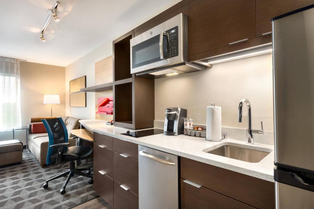 a kitchen with a sink and a living room at TownePlace Suites by Marriott Milwaukee Grafton in Grafton