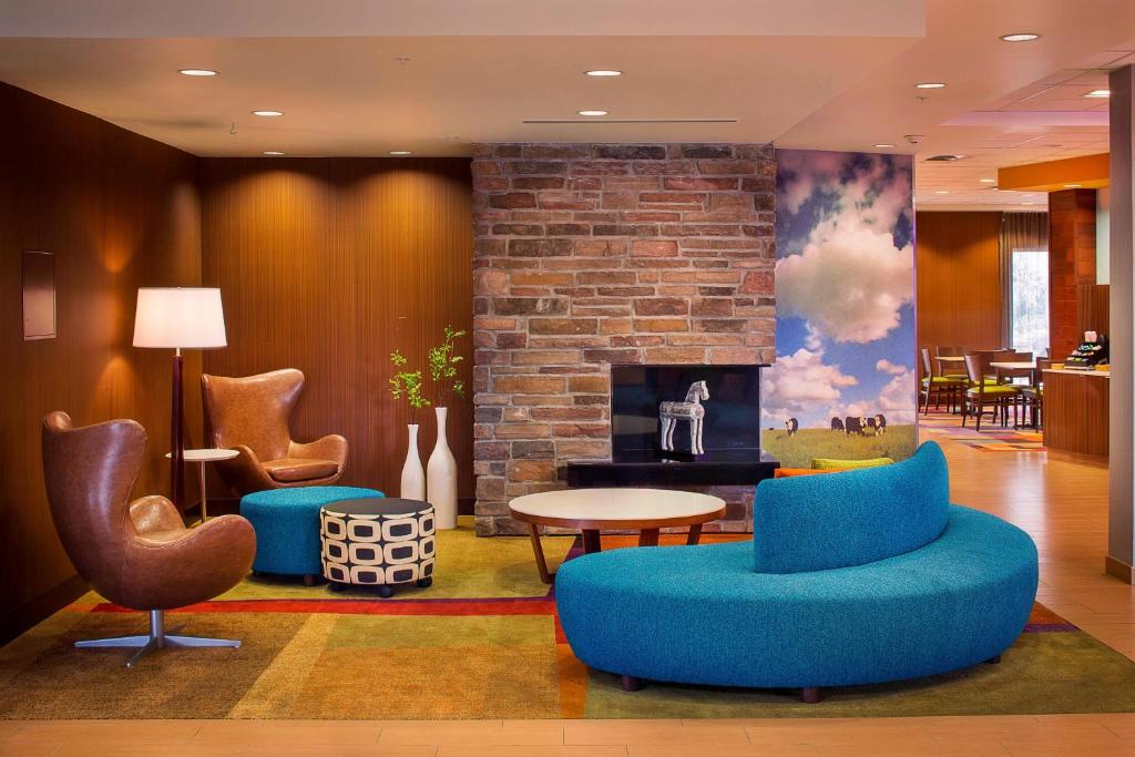 a lobby with chairs tables and a fireplace at Fairfield Inn and Suites by Marriott Monaca in Monaca