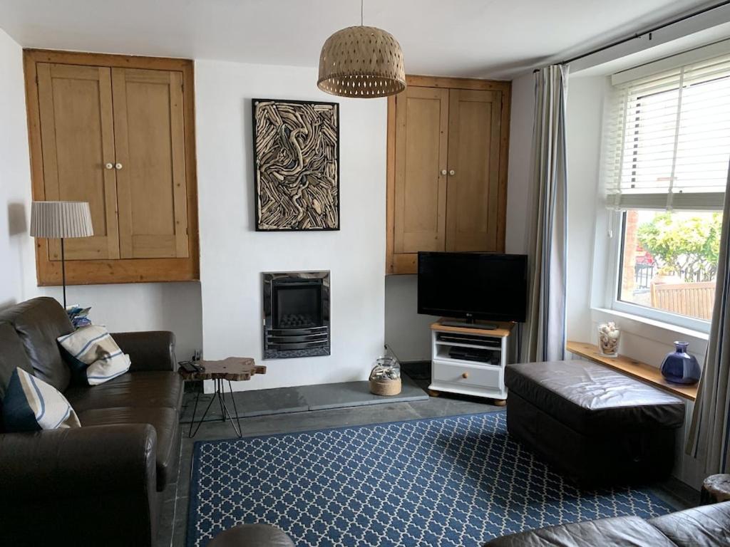 a living room with a couch and a television at Seasalt Cottage - Modernised traditional cottage, Sleeps 5,short walk to beaches, town, amenities in Pembrokeshire