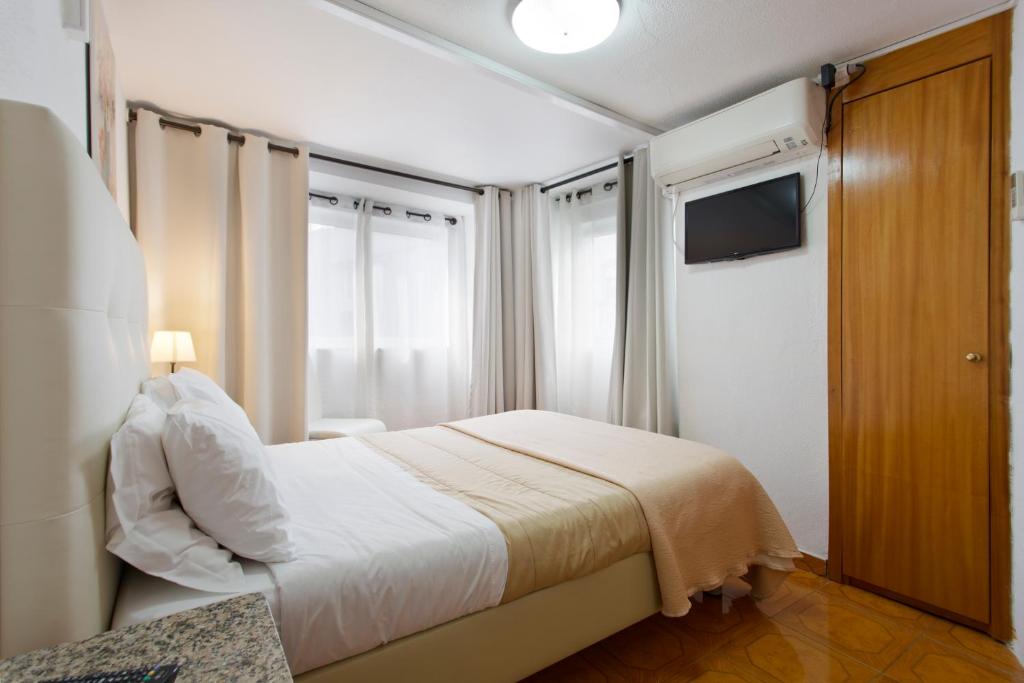 Braganca Oporto في بورتو: غرفة نوم صغيرة بها سرير وتلفزيون