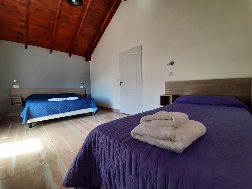 Un dormitorio con una cama morada con toallas. en FLORES PATAGONICAS departamentos en El Calafate