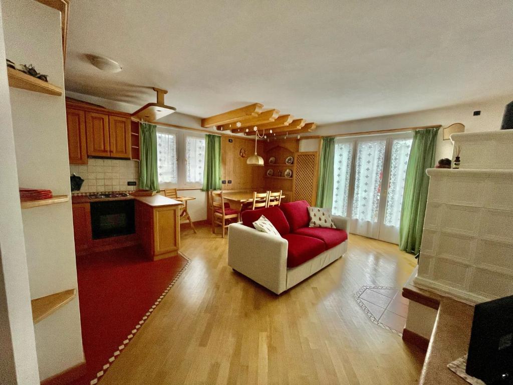 Villa Iris Asiago - giardino e parcheggio في أسياجو: غرفة معيشة مع أريكة حمراء ومطبخ