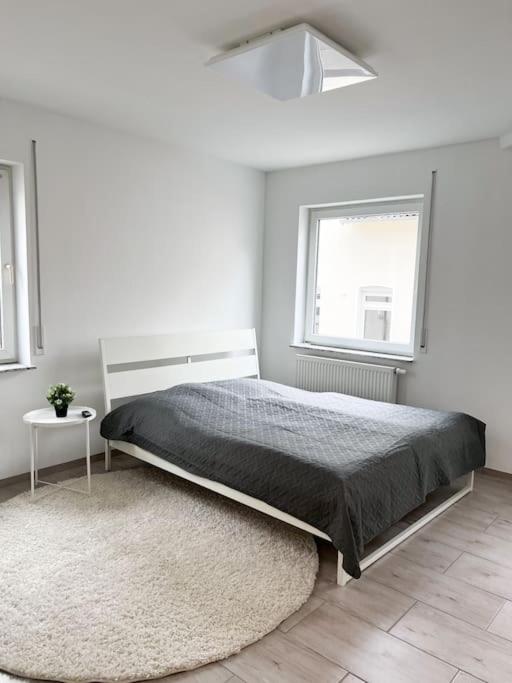 a white bedroom with a bed and a window at Neu sanierte Einzimmerwohnung in Bad Nauheim