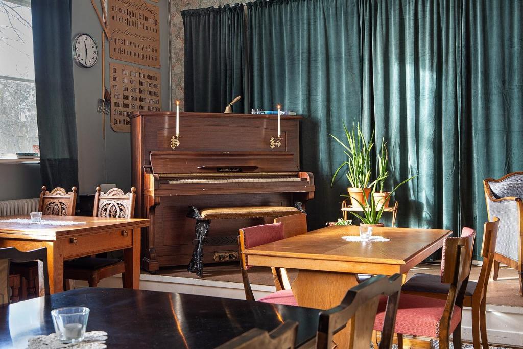 um piano numa sala com mesas e cadeiras em Edith och Julia B&B em Rälla