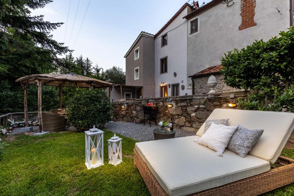 un canapé blanc assis dans l'herbe dans une cour dans l'établissement Rio delle Fate, a Fairytale Home along the Stream in Vorno, Lucca, à Capannori
